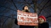 In November 2019, a woman in Moscow holds a  banner that demands Russia adopt a law against domestic violence. "They haven't killed us yet," the poster reads. 