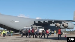 Гватемальцы сходят с американского военного самолета после депортации из США, 24 января 2025 года