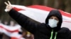 A man carrying a former white-red-white flag of Belarus gestures the V-sign in Minsk, on December 13, 2020. 