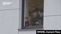 A group of detained illegal migrants inside Latvia's Mucenieki migrant detention center respond to media outside the center's gates.