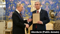 Президент России Владимир Путин вручает президенту Казахстана Касым-Жомарту Токаеву наградной лист его отца Кемеля Токаева. Москва, 9 мая 2025 года