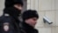 Police officers walk past a surveillance camera in downtown Moscow on January 26, 2020. 