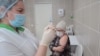 A nurse at Russia's Kemerovo Clinical Diagnostic Center prepares to vaccinate fellow nurse Olga Skripachenko  with the Sputnik-V vaccine on December 9, 2020.
